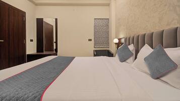 Habitación de hotel con una cama grande, un armario de madera, un espejo, una lámpara de pared y un adorno mural con diseño.