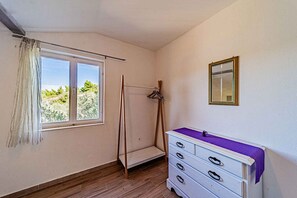 A room with a window, a wooden wardrobe, and a mirror on the wall. - Holiday Apartment Holiday Apartment Ivana near the beach (Vela Luka)