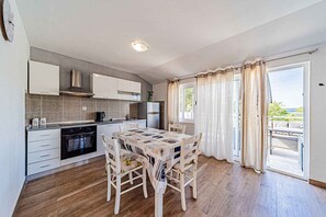 A modern kitchen with a dining area, wooden flooring, and a view of the outdoors. - Holiday Apartment Holiday Apartment Ivana near the beach (Vela Luka)