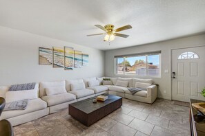 A living room with a sectional sofa, a coffee table, and a ceiling fan. - Havasu Sahara - Pool, BBQ, Cozy Living Space (Lake Havasu City)