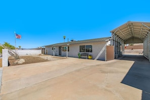 A single-story building with a covered outdoor area, a flag, and a bench. - Havasu Sahara - Pool, BBQ, Cozy Living Space (Lake Havasu City)