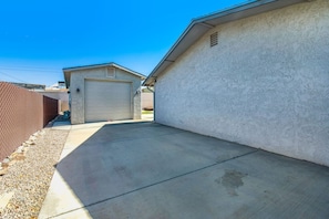 A residential garage with a concrete driveway, a brick wall, and a clear blue sky. - Havasu Sahara - Pool, BBQ, Cozy Living Space (Lake Havasu City)
