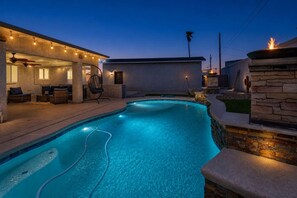 A swimming pool with a stone wall and a patio area with seating. - Havasu Sahara - Pool, BBQ, Cozy Living Space (Lake Havasu City)