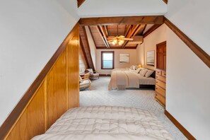 Een slaapkamer met schuine wanden, een bed, een kast en een raam.