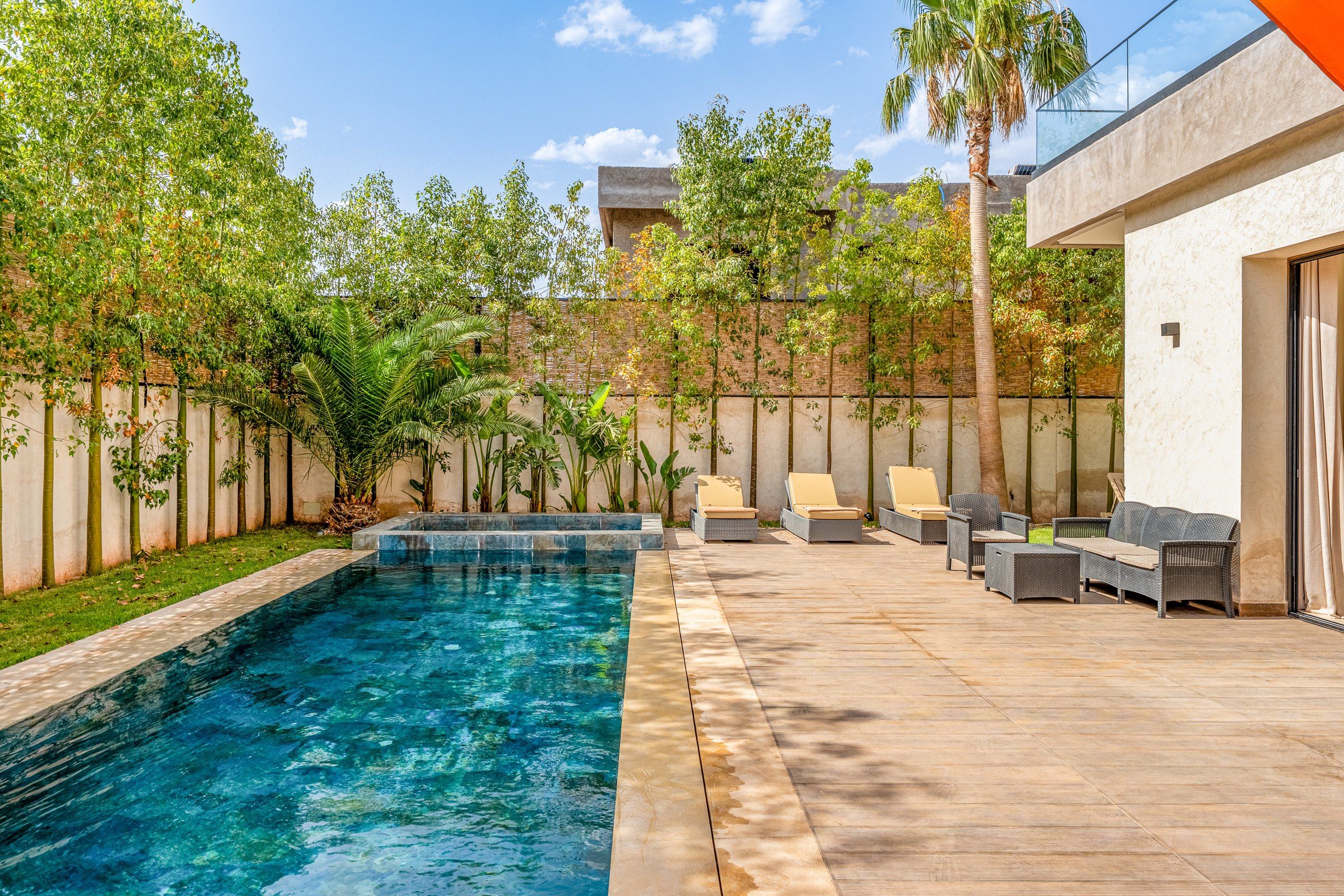 A swimming pool with a wooden deck and lounge chairs.