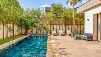 A swimming pool with a wooden deck and lounge chairs.
