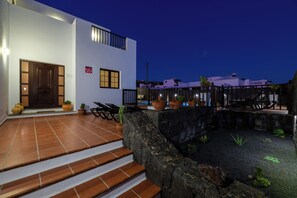 A modern building with a white exterior, a stone wall, and a small garden area with potted plants. - Villa Europa: Private Pool and Space for Families and Groups (Nazaret)