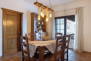 A dining area with a wooden table, chairs, a chandelier, and a view through a glass door. - Vrbo Property (Nazaret)