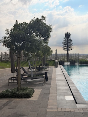 Zona de piscina amb gandules, un arbre i una tanca.