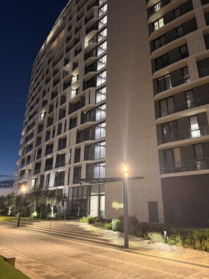A multi-story hotel building with balconies, a well-lit entrance, and a landscaped area with steps leading to the entrance. - Riviera Château de Rêve - Phoenix's Gîte @ Ellipse Waterfall. (Midrand)
