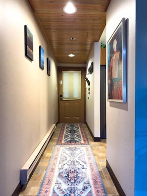 A hallway with a patterned rug, framed pictures on the walls, and a wooden ceiling. - 3BR Big Sky Condo Sleeps 9, Walk to Free Shuttle (Big Sky)