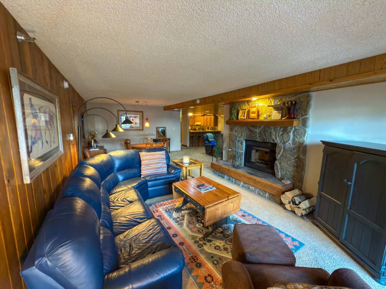 A cozy living room with a fireplace, leather sofas, and a coffee table.