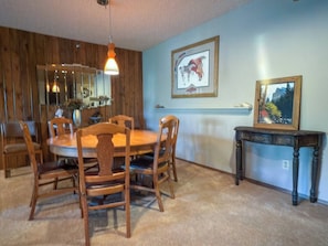 A dining area with a wooden table and chairs, a mirror, and two framed pictures on the wall. - 3BR Big Sky Condo Sleeps 9, Walk to Free Shuttle (Big Sky)