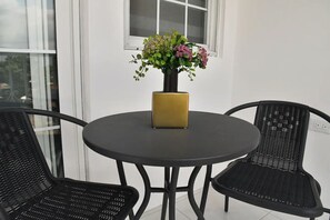 A round table with a laptop, two chairs, and a potted plant with flowers. - Cozy apartment with AC close to good food, supermarket and local attractions (Kingston)