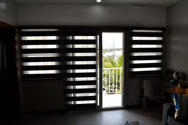 A room with a sliding door leading to a balcony, a desk with a chair, and a small table with a globe and a plant. - Cozy apartment with AC close to good food, supermarket and local attractions (Kingston)