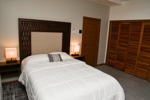 A hotel room with a large bed, a wooden headboard, two bedside tables with lamps, a wardrobe, and a rug. - Cozy apartment with AC close to good food, supermarket and local attractions (Kingston)