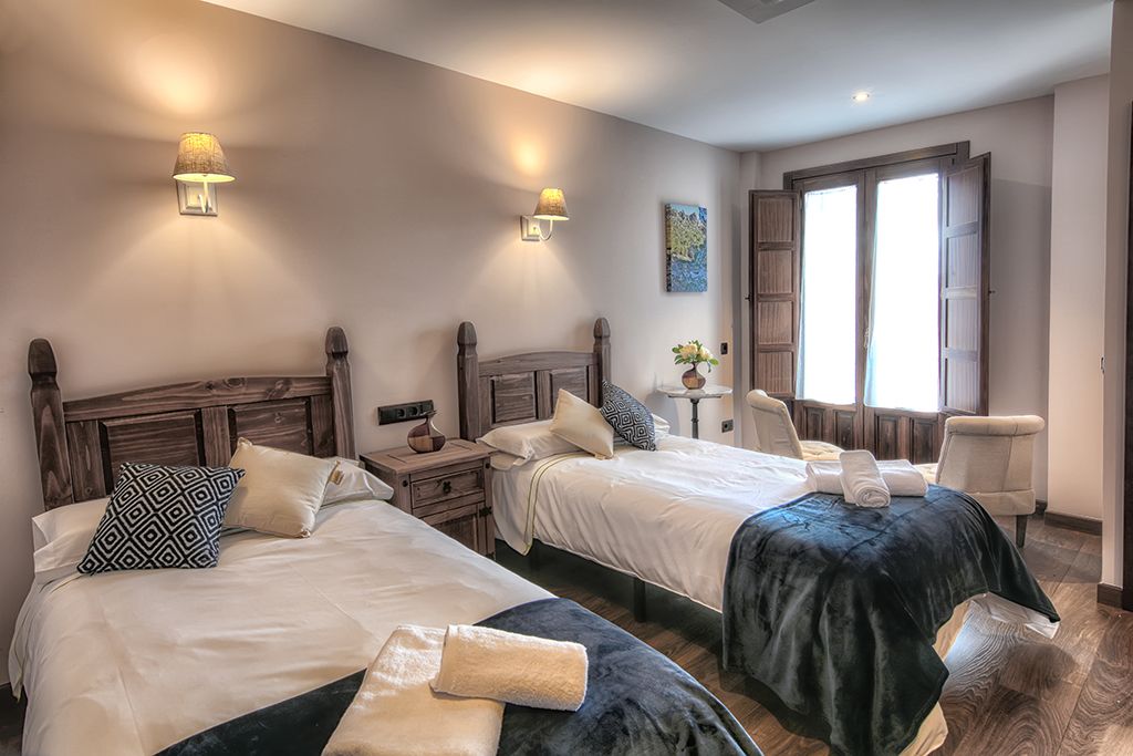 A hotel room with two beds, a sitting area, and a window with curtains.