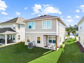 A two-story residential building with a covered patio and a small lawn. - New home—5 minutes from the beach, Pier Park, and Walmart; includes an arcade room, balcony, and work area*pets allowed (Panama City beach)