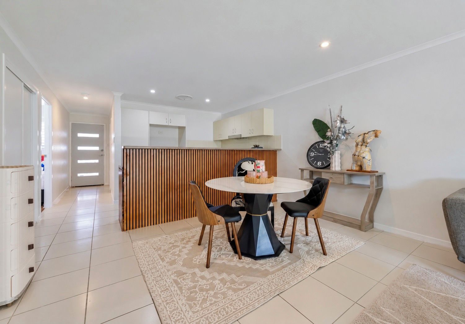 A modern dining area with a round table, two chairs, and a decorative centerpiece.