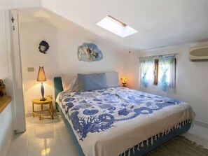 A bedroom with a bed, a bedside table, a lamp, a window with curtains, a wall decoration, and a ceiling light. - Nice apartment for 6 people with A/C, pool and patio (Olbia)
