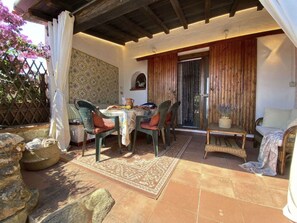 Eine Außenpatio-Terrasse mit Tisch und Stühlen, einer Holztür und einer Wand mit Muster.