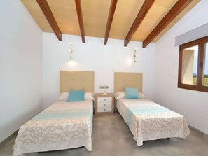 Ein Schlafzimmer mit zwei Betten, Holzbalkendecke, Nachttischen und einem Fenster.