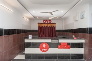 Zona de recepción con mostrador de entrada, ventilador de techo y cartel con el horario de atención.