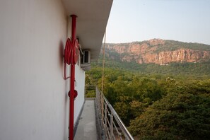 A balcony with a red hose, a white wall, and a view of a forested mountain. - Collection O Srinivasa Residency (Tirupati)