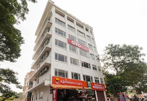 Un edificio de varios pisos con un restaurante llamado 'Krishna Cafe' en la planta baja y un letrero que indica 'Srinivasa Residency' en los pisos superiores.