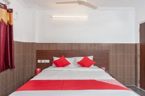 A hotel room with a bed, a ceiling fan, and a night light. - Collection O Srinivasa Residency (Tirupati)