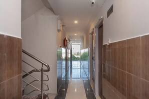 Un pasillo con una escalera metálica a la izquierda, un extintor de incendios en la pared y una puerta a la derecha.