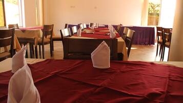 Un comedor con mesas dispuestas para el servicio, sillas alrededor y una ventana que proporciona luz natural.