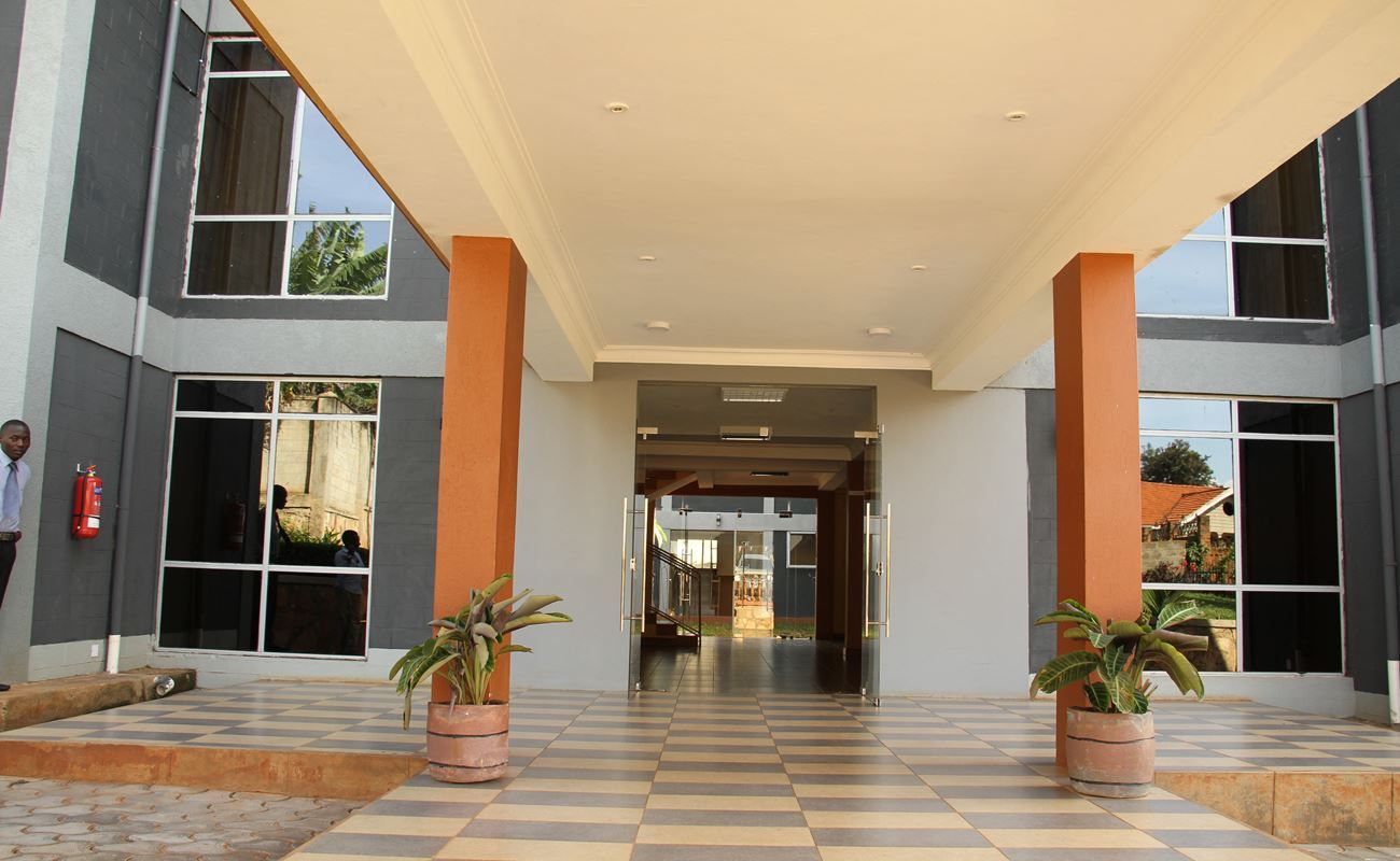 A building entrance with a checkered floor, large windows, and potted plants.