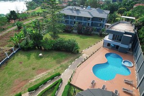 Una propiedad residencial con piscina, jardín cercado y una casa grande con muchas ventanas.