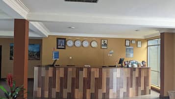 Un mostrador de recepción con un reloj, cuadros enmarcados y una computadora.