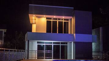 A modern two-story building with a large entrance and a swimming pool in the foreground.