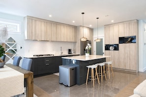 A modern kitchen with a central island, bar stools, and pendant lighting.