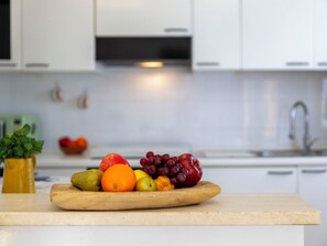 A kitchen counter with a wooden cutting board holding fruits and vegetables. - Morosita Home by Interhome (Alghero)