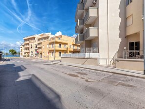 A multi-story residential building with balconies, a clear sky, and a street in front. - Morosita Home by Interhome (Alghero)