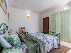 Ein Schlafzimmer mit Bett, Stuhl, Kleiderschrank und einem Gemälde an der Wand.