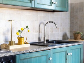 A kitchen with teal cabinets, a granite countertop, a stainless steel sink, and a yellow vase with lemons. - Il Giardino di Sabrina by Interhome (Valledoria)