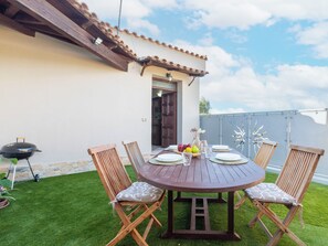 An outdoor dining area with a round wooden table, six wooden chairs, and a barbecue grill. - Il Giardino di Sabrina by Interhome (Valledoria)