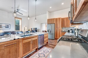 A modern kitchen with wooden cabinets, a stainless steel refrigerator, a built-in oven, and a marble countertop. - Sanctuary Stay: A Historic Converted Church in Downtown Salida (Salida)
