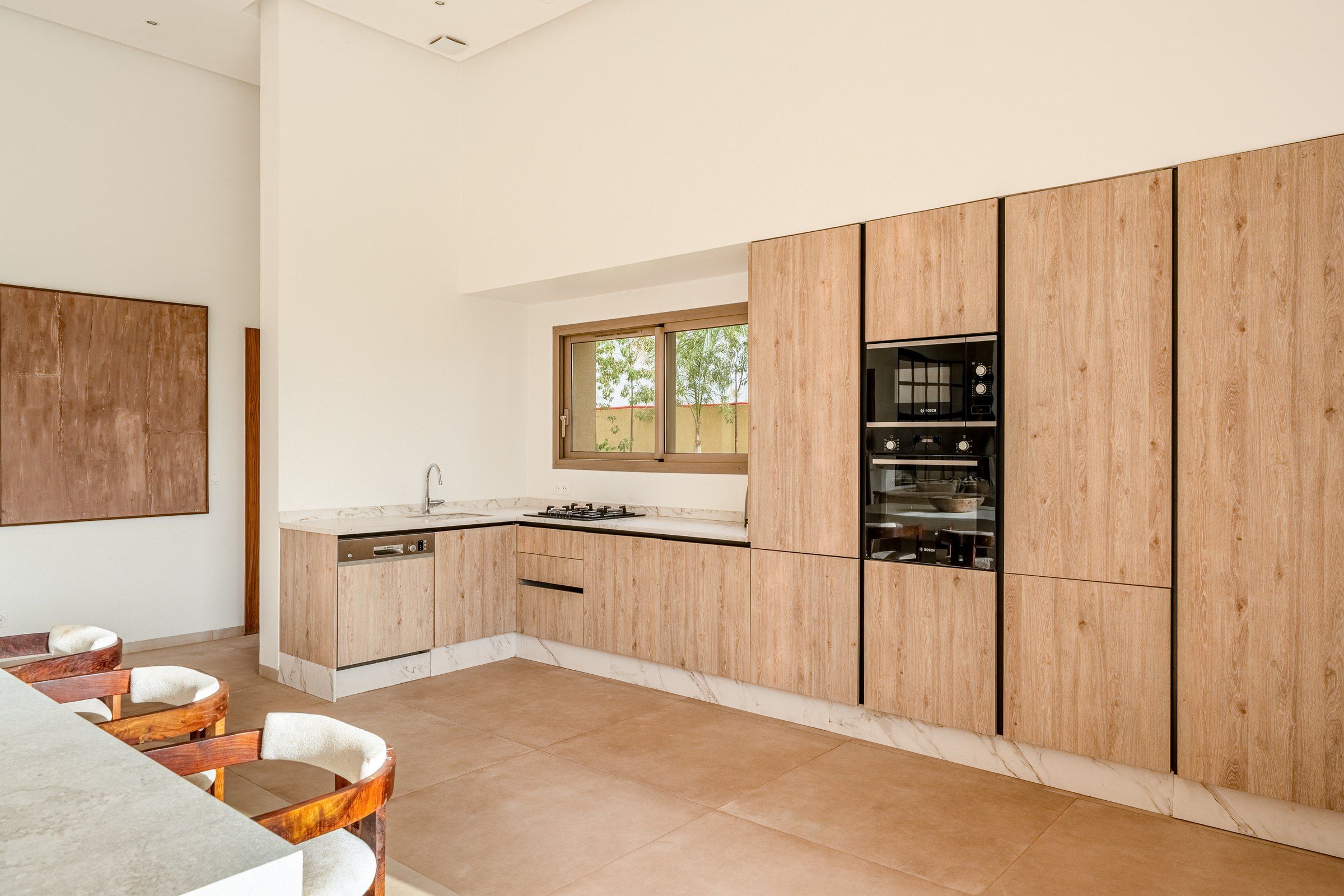 Une cuisine moderne avec des meubles en bois, un four encastré et une fenêtre.