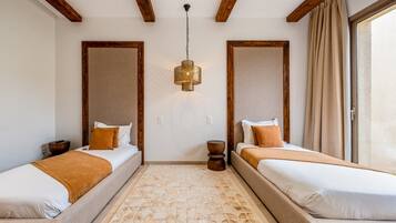 A hotel room with two beds, a patterned rug, a hanging light fixture, and wooden beams on the ceiling.