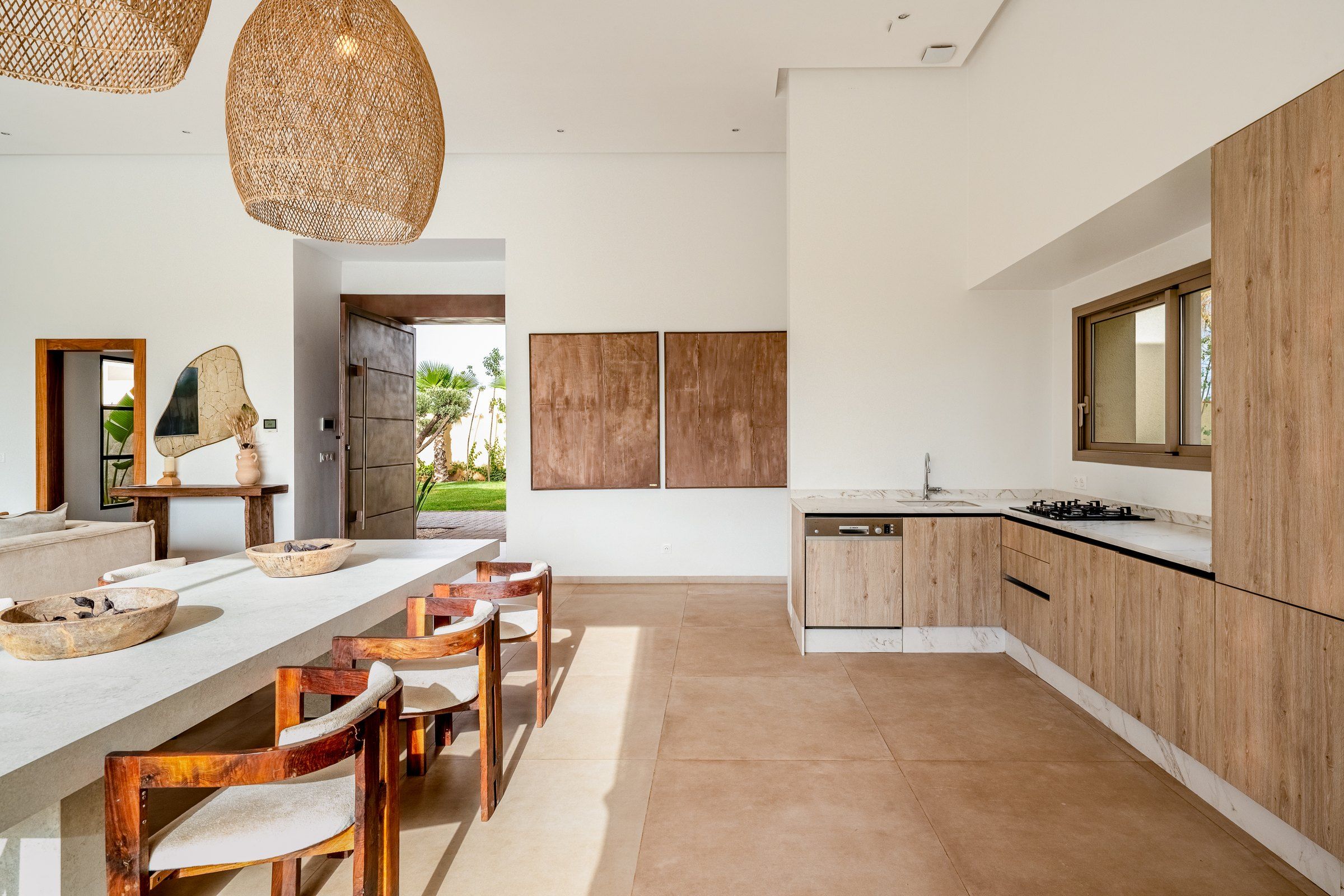 A modern kitchen with a central island, wooden cabinets, and a large window.