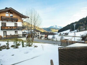 Schneebedeckte Landschaft mit einem Holzbau und einem Berg im Hintergrund.