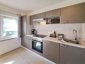 A modern kitchen with stainless steel appliances, a built-in oven, a coffee maker, and a sink. - Almenland by Interhome (Auffach)