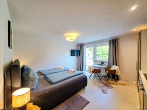 A bedroom with a bed, a desk, a chair, a TV, and a window. - Bärenhöhle by Interhome (Auffach)