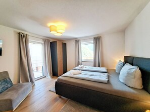 A hotel room with a bed, a chair, a window, and a wall-mounted light fixture. - Bienenwiese by Interhome (Auffach)